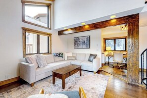 Ein modernes Wohnzimmer mit einem Ecksofa, einem Couchtisch und einem großen Fenster.
