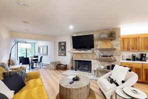 A living room with a fireplace, a television, and a dining area. - Cozy condo with full kitchen, fast wifi & W/D - great location (Vail)