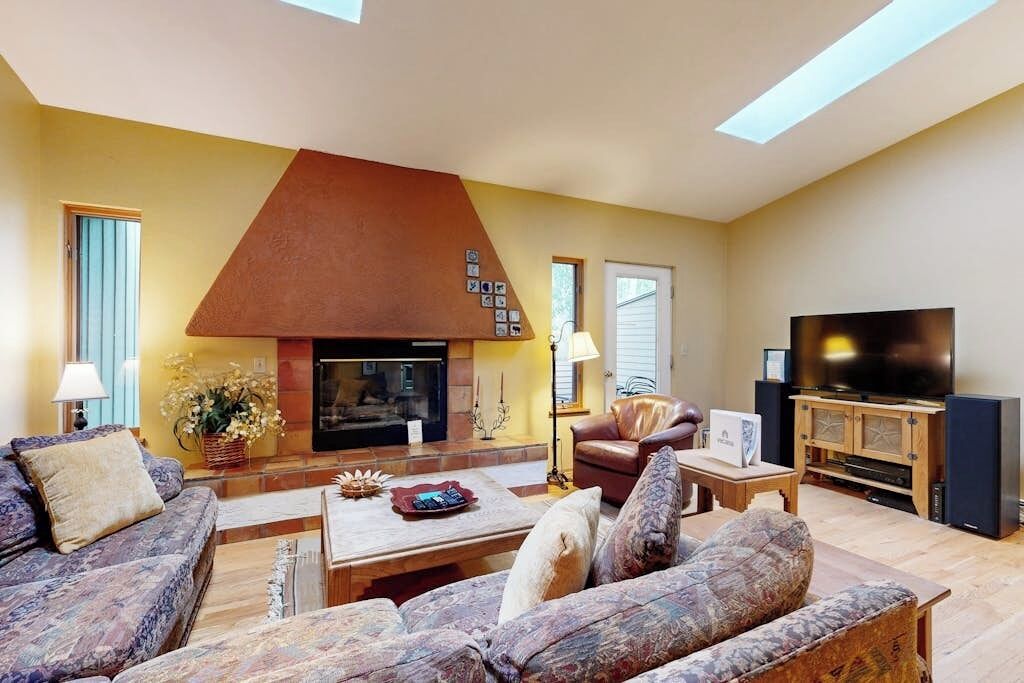 A living room with a fireplace, sofas, a television, and a wooden cabinet.