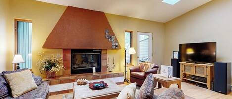 A living room with a fireplace, sofas, a television, and a wooden cabinet.