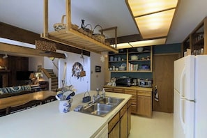 Eine Küche mit Holzschränken, einem weißen Kühlschrank, einer Mikrowelle und einem Spülbecken.