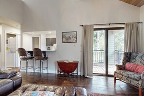 A spacious living area with a leather couch, a patterned armchair, a dining table with chairs, and a large window with curtains. - Newly Renovated Condo - on the Bus Line (Vail)