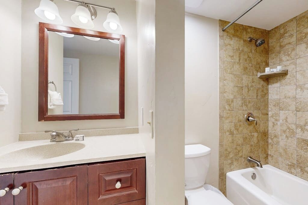 A bathroom with a sink, mirror, vanity, toilet, and bathtub.