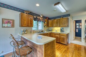 A kitchen with wooden cabinets, a bar stool, a built-in island, and a window. - Secluded valley home w/ private balcony, grill, shared tennis - close to trails (East Vail)