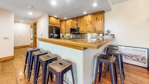 Une cuisine avec des meubles en bois, un îlot central doté de tabourets et un réfrigérateur.