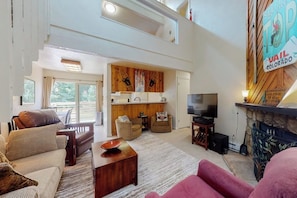 Ein geräumiges Wohnzimmer mit Kamin, Fernseher und Essbereich mit Holztisch und Stühlen.