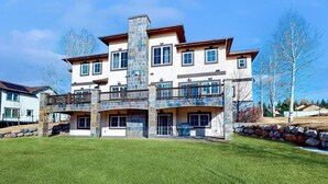 Ein mehrgeschossiges Haus mit einer Steinaußenwand, mehreren Balkonen und einem gepflegten Rasen.