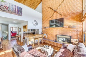 Ein geräumiges Wohnzimmer mit Kamin, Essbereich und einer Küche im Hintergrund.