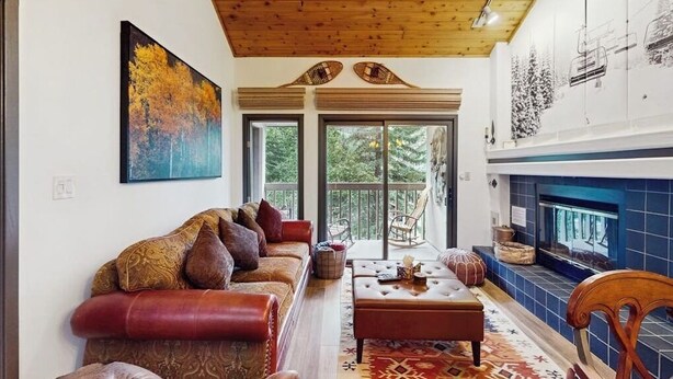 Una sala de estar con sofá, reposapiés y chimenea.