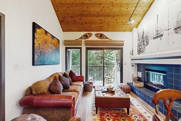 A living room with a sofa, ottoman, and fireplace. - Spacious condo w/ full kitchen, shared hot tub & perfect location (Beaver Creek)