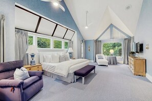 Ein Schlafzimmer mit einem großen Bett, einer Couch, einem Schreibtisch und einem Sessel.