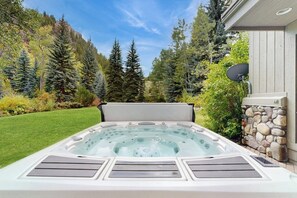Ein Whirlpool in einem Garten mit einer Steinmauer, einer Satellitenschüssel und Bergblick.