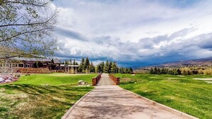 A golf course with a concrete pathway leading to a clubhouse. - All-season condo near ski lifts & golf course, with pool, & hot tub (Edwards)