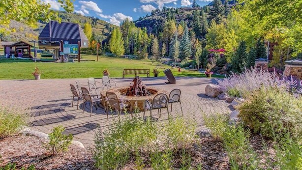A patio with outdoor seating, a fire pit, and a view of a mountain. - All-season condo near ski lifts & golf course, with pool, & hot tub (Edwards)