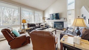 Ein Wohnzimmer mit Kamin, zwei Sofas, einem Relaxsessel und einem Couchtisch.