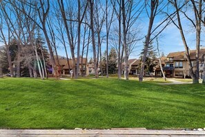 A residential area with a grassy lawn, leafless trees, and multi-story buildings in the background. - Conveniently located condo w/ full kitchen & fast wifi - near skiing and golf (Avon)
