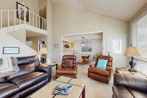 A spacious living room with leather sofas, a coffee table, and a staircase leading to an upper level. - Conveniently located condo w/ full kitchen & fast wifi - near skiing and golf (Avon)