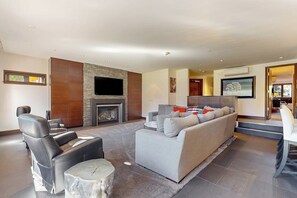 Ein modernes Wohnzimmer mit Kamin, Ledersofas und einem Flachbildfernseher.