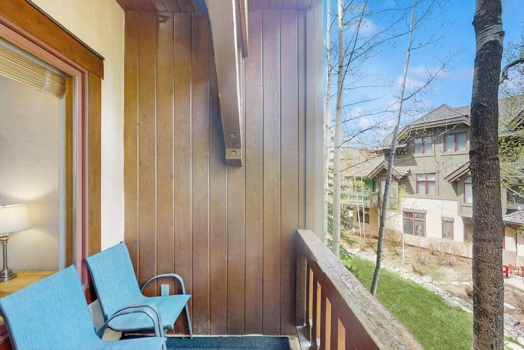 A balcony with wooden railings, a chair, and a table.