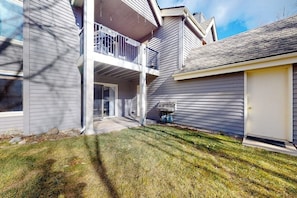 A two-story residential building with a covered patio, a garage, and a well-maintained lawn. - Riverfront, ground-floor condo with fireplace & fishing access - near Riverwalk (Edwards)