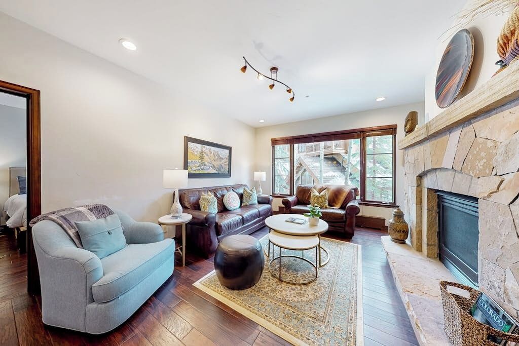 A living room with a fireplace, a sofa, a coffee table, and a rug.