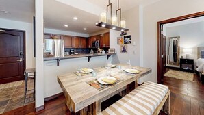 A dining area with a wooden table, bench, and hanging light fixture. - Ski in/out mountain getaway with pool, hot tub, & balcony - steps to the slopes (Edwards)
