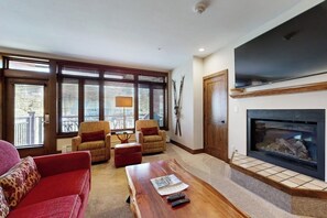 Ein Wohnzimmer mit Kamin, einer Couch, einem Couchtisch und einem Fernseher.