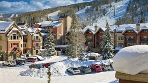 Un complexe hôtelier composé d’immeubles à plusieurs étages, d’un parking et offrant une vue sur une montagne enneigée.