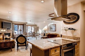 A spacious living area with a large island, a fireplace, and a dining area with chairs. - Winter Condo in Ski-In/Ski-Out Complex w/Fireplace/Free WiFi/Shared Pool/Hot Tub (Vail)