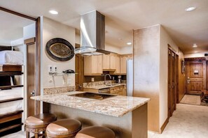 A compact kitchen with a central island, wooden cabinets, and a stainless steel range hood. - Winter Condo in Ski-In/Ski-Out Complex w/Fireplace/Free WiFi/Shared Pool/Hot Tub (Vail)