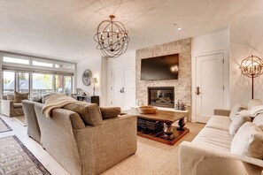 A modern living room with sofas, a fireplace, and a large TV. - Ski-in/out home with fireplace, AC, high-speed WiFi, shared pool/hot tub/laundry (Vail)