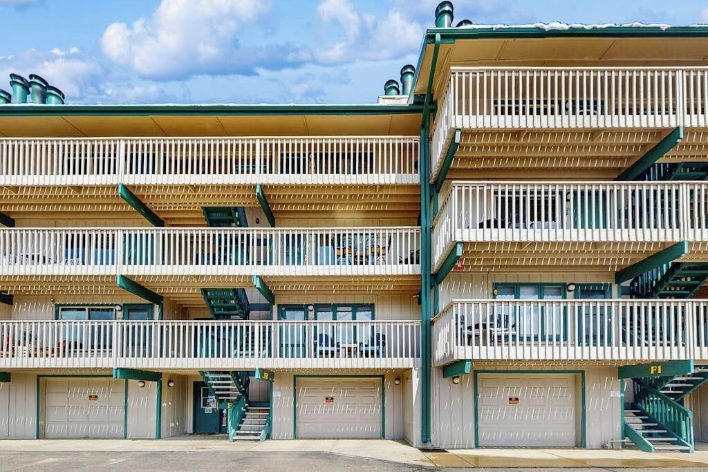 Un motel à plusieurs étages, doté de balcons, d’un parking et d’un escalier menant aux étages supérieurs.