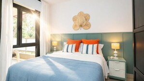 Un dormitorio con una cama, dos mesitas de noche, un adorno en la pared y una ventana con cortinas.
