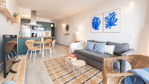 Una sala moderna con sofá, mesa de comedor, sillas y una cocina al fondo.