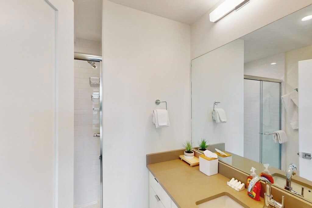Een moderne badkamer met een grote spiegel, een wastafel, een douche en een toilet.