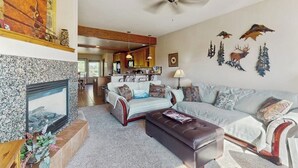 Ein Wohnzimmer mit Kamin, einer Couch, einem Couchtisch und einem Deckenventilator.
