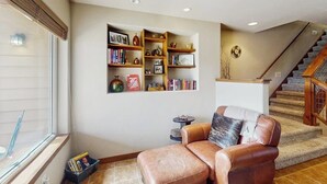 Ein Wohnzimmer mit Ledersofa, Bücherregal und Treppe.