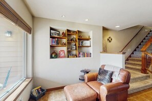 Ein Wohnzimmer mit Ledersofa, Bücherregal und Treppe.