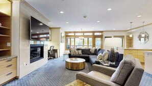 A modern living room with a fireplace, sofa, coffee table, and a flat-screen TV mounted on the wall. - Ski-in/out condo with fireplace, balcony, fast WiFi & shared hot tub, pool, W/D (Vail)