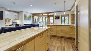 A modern kitchen with wooden cabinets, a marble countertop, and pendant lighting. - Ski-in/out condo with fireplace, balcony, fast WiFi & shared hot tub, pool, W/D (Vail)