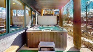 A hot tub with a wooden exterior, a bench, and a view of a snowy landscape. - Enchanting mountain oasis with hot tub, fireplaces, deck, & views (Fraser)