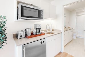 A modern kitchen with a microwave, toaster, coffee maker, and dishwasher. - Modern ground-floor studio with mountain view, kitchenette & parking (Fraser)