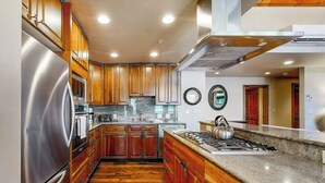 A kitchen with wooden cabinets, a stainless steel refrigerator, a gas stove, and a microwave. - Ski-in/ski-out condo w/ balcony, fireplace, fast WiFi, W/D & shared pool/hot tub (Vail)