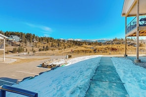 A snow-covered pathway leading to a building with a view of a mountainous landscape. - Mountain-view condo with private hot tub & heated 1-car garage with EV charger (Fraser)