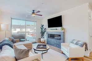 A modern living room with a sofa, armchair, coffee table, and fireplace. - Mountain-view condo with private hot tub & heated 1-car garage with EV charger (Fraser)