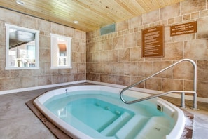 Ein Spa-Bereich mit Whirlpool, gefliesten Wänden, Holzboden und einem Fenster.