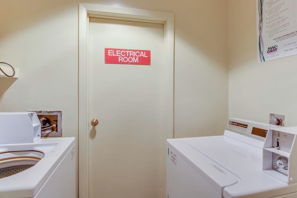 Una habitación con un letrero que dice 'ELECTRICAL ROOM', una lavadora y una secadora.