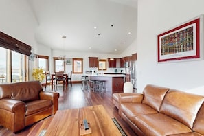 Ein geräumiger Wohnbereich mit Ledersofas, einem Holztisch und einer Küche im Hintergrund.