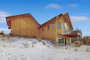 Ein modernes Holzhaus mit einer großen Terrasse und einem Steinfundament.