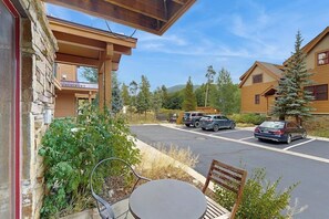 A building with a stone facade, a covered outdoor seating area, and a parking lot with cars. - Antlers Gulch Townhouse Next to National Forest & Golf w/shared Hot Tub, WiFi (Keystone)